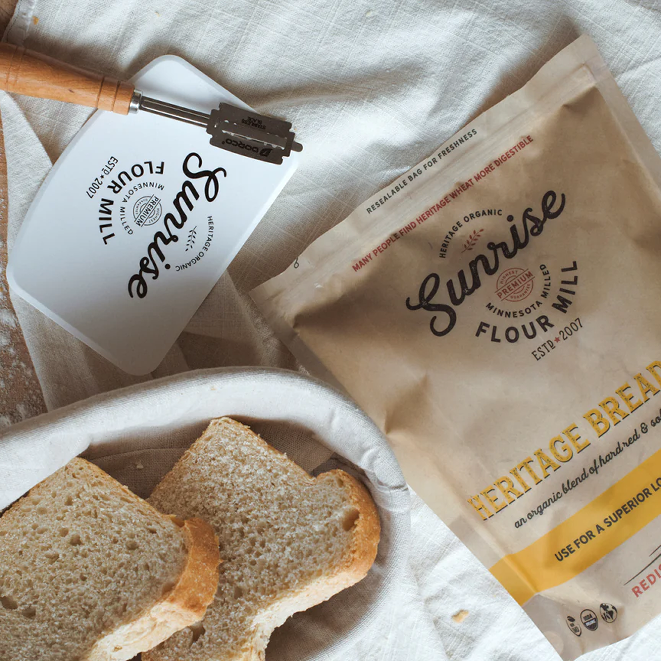 Flour packaging, bread slices, and a bread-making tool on a table.