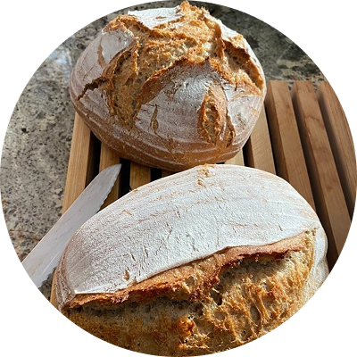 Two freshly baked sourdough loaves on a wooden rack.